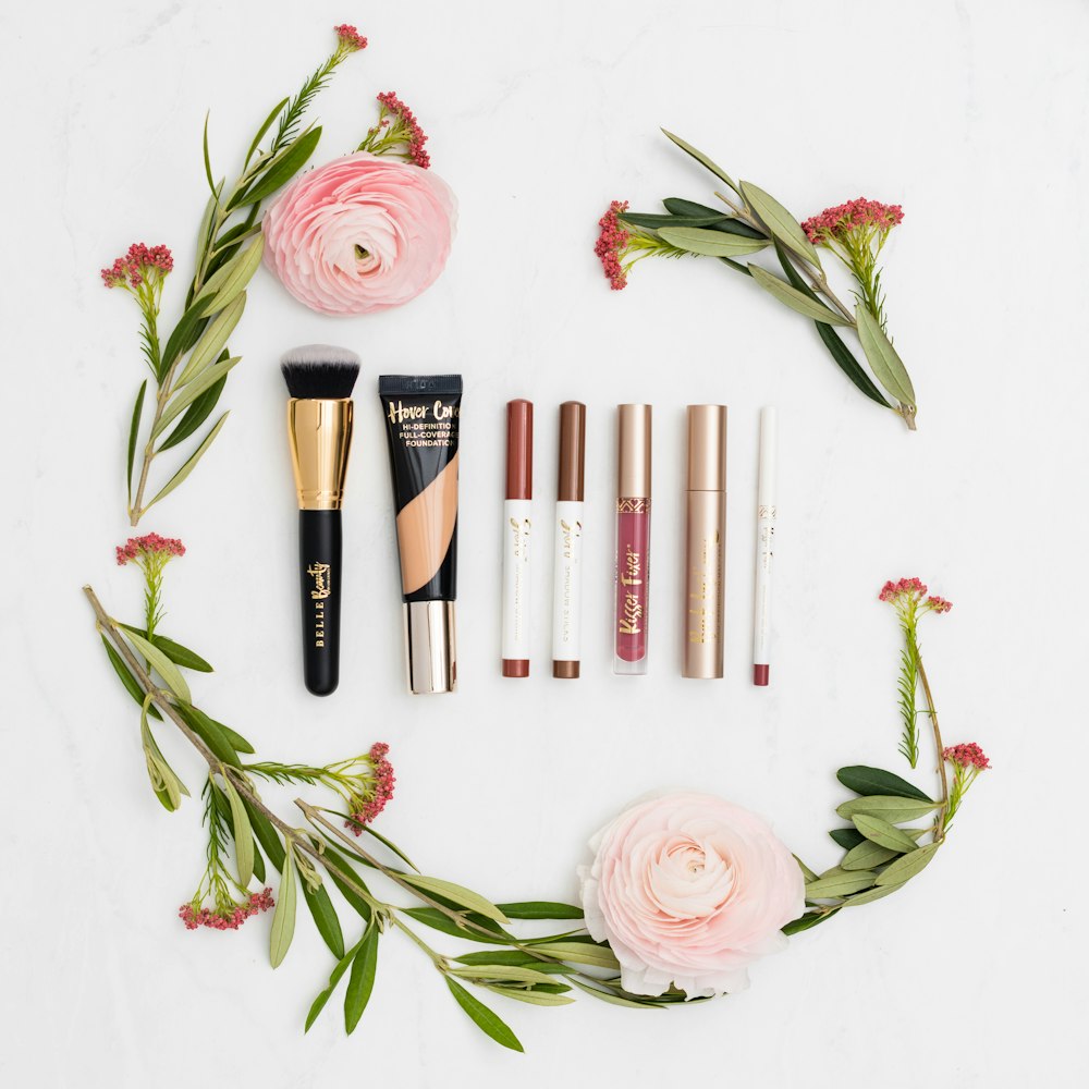 Elegant flatlay of makeup products styled with pink flowers